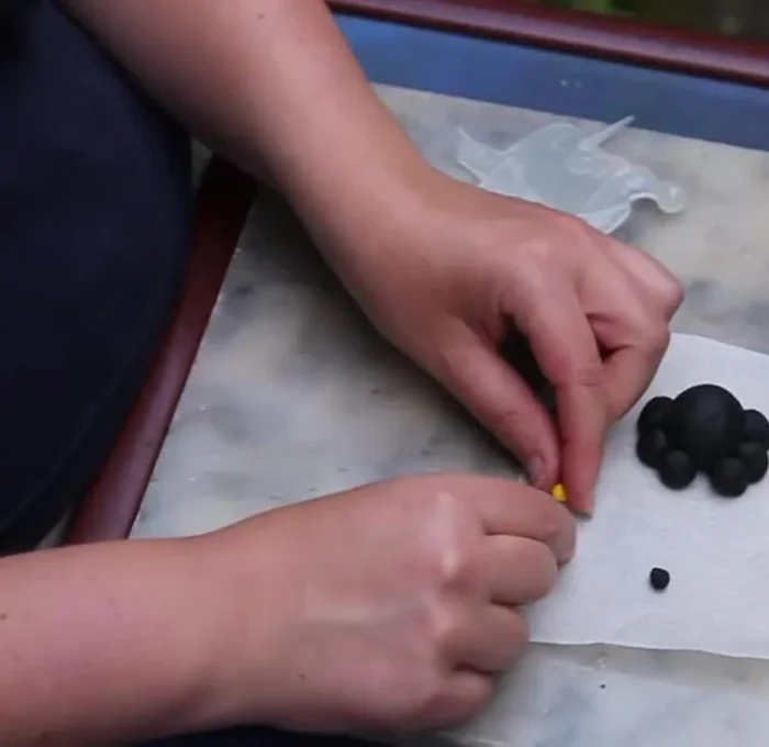 Roll out a thin sausage of black clay and cut two small pieces for the pupils. Attach to the eyes.