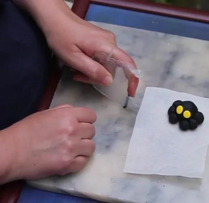 Roll out a thin sausage of black clay and cut two small pieces for the pupils. Attach to the eyes.