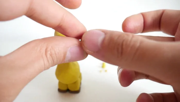 Create horns (ossicones) from small yellow clay strips, adding small brown clay balls to the tips.