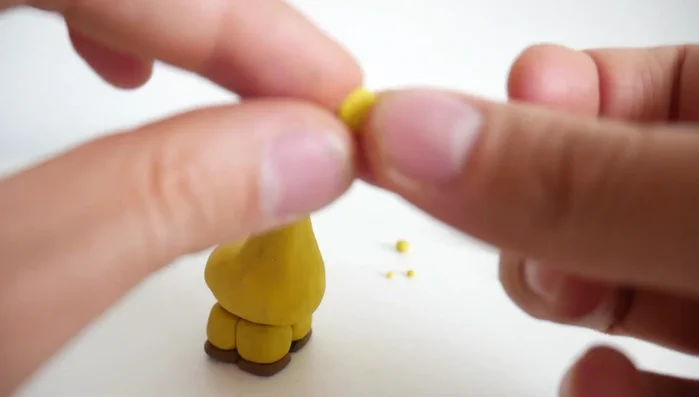 Create horns (ossicones) from small yellow clay strips, adding small brown clay balls to the tips.