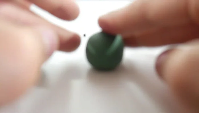 Shape the head: Flatten the other large green ball into an oval for the head. [39.899]