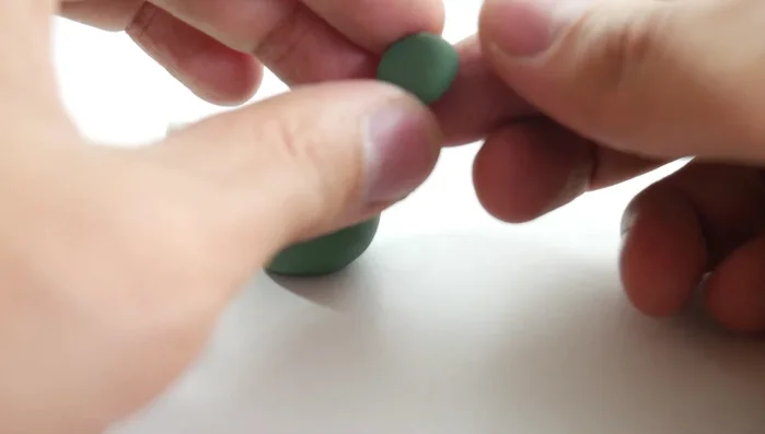 Create the eyes: Flatten a small green ball into a circle. Top with a smaller flattened white ball, then an even smaller flattened black ball for the pupils. [51.12]