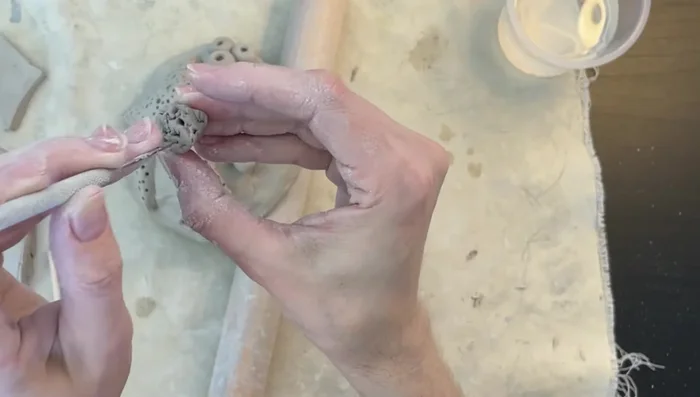 Create brain coral: Roll small clay balls and use a dowel and needle tool to create holes, resembling brain coral. Attach using the score and slip method.