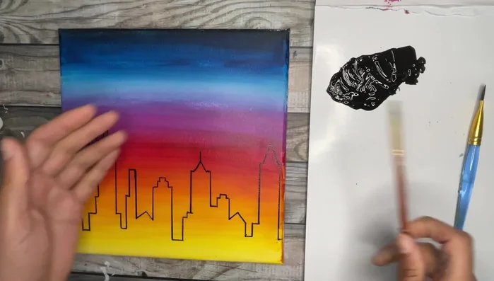Paint cityscape using thinned-down black paint and flat brush, using the chiseled edge to create crisp lines. Rotate canvas as needed.