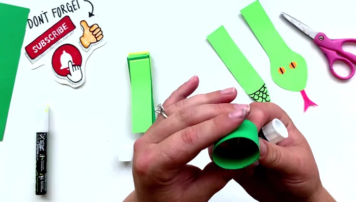 Assemble the paper chain: Apply glue to one end of a paper strip, roll it into a circle, and glue it to the other side. Repeat this process, linking the rings together to form a chain.