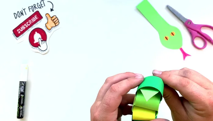 Attach the head and tail: Slide the head and tail pieces through the ends of the paper chain and secure them with glue.