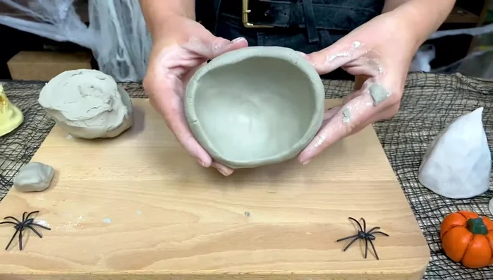 Shape the pinch pots: Once you have two bowl shapes, smooth out cracks and creases. Pinch and roll outwards the rim of one bowl.