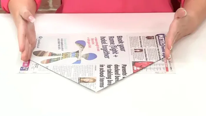 Turn the paper over. Fold the side flaps inwards, the amount you fold will determine the hat size. Repeat on the other side.
