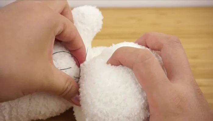 Cut out two leaf shapes from the remaining sock, backstitch, and turn inside out to create ears. Attach to the head.