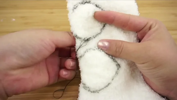 Cut out two leaf shapes from the remaining sock, backstitch, and turn inside out to create ears. Attach to the head.