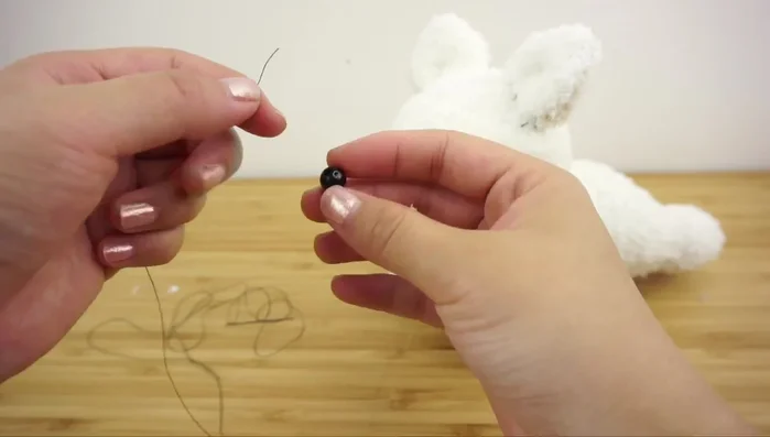 Attach beads or buttons for eyes, using a single thread and creating slight tension for symmetry.