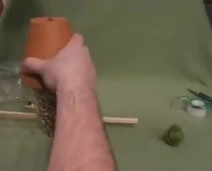 Place the filled terracotta pot on top of the dowel and spoons.