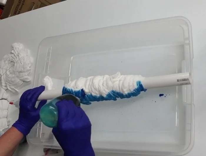 Place the PVC pipe with the rolled shirt over a plastic tub to catch excess dye.