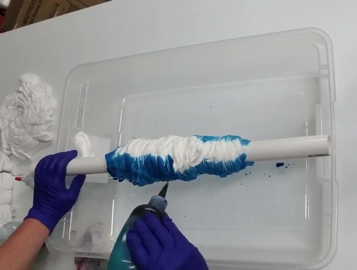 Apply turquoise dye, turning the pipe to coat the entire shirt. Avoid over-saturation.