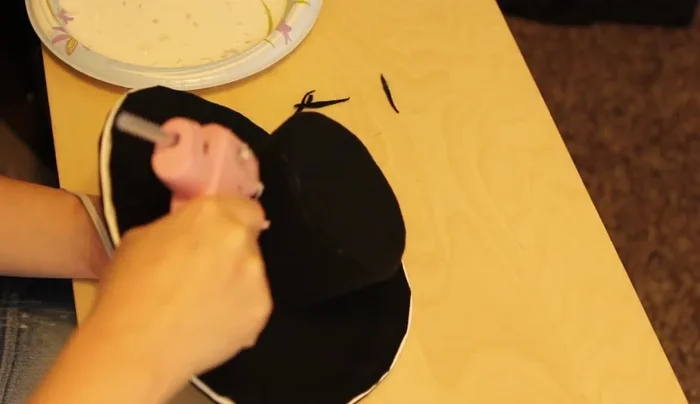 Shape the hat: Glue the brim to the wall, starting at the back. Hold for at least a minute. Add barrette clips or combs to secure the hat to the head.