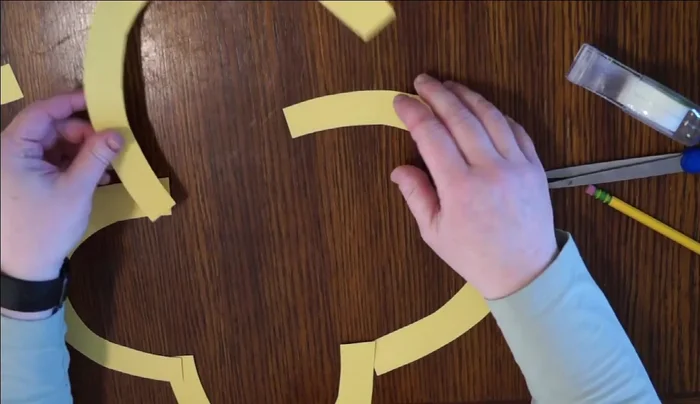 Assemble flower frame: Arrange five of the largest arcs to create a flower shape, with the cut sides facing inwards. Secure the joints with tape. Set aside one smaller arc.