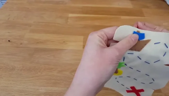 Attach the final piece (ship's sail) using the felt stitch. The felt stitch involves bringing the needle up, knotting, going down under the fabric, leaving a small stitch, and repeating.