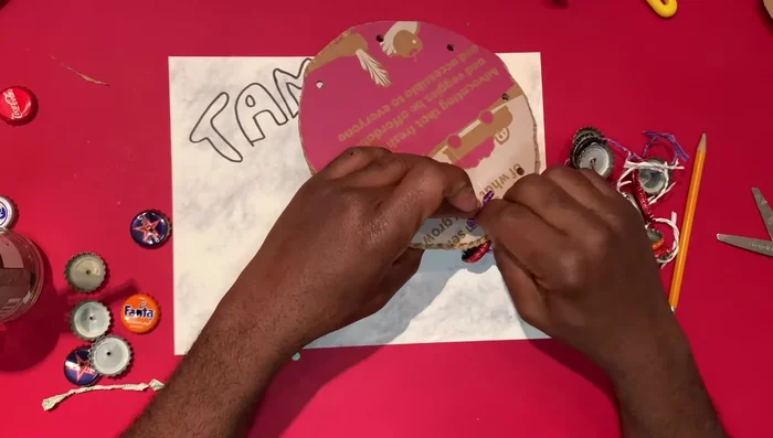 Tie the jingles into the holes of the cardboard tambourine.