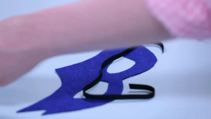 Cut a piece of elastic and attach it to the mask using squares of self-adhesive felt.